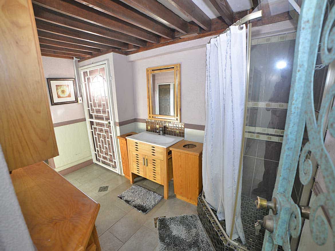Cozy Bathroom with Rustic Decor Cornerstone- Small bathroom with wooden accents, mirror, and shower curtain.