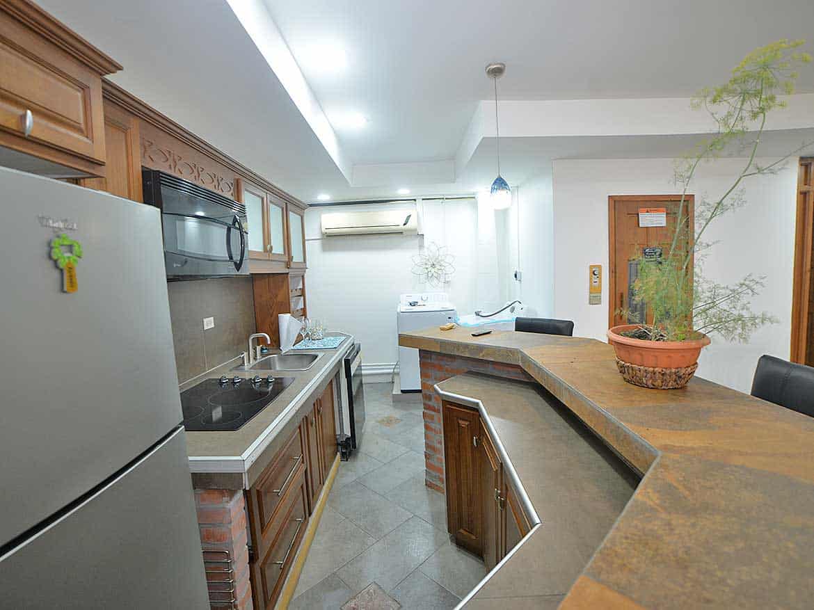 Modern Kitchen in 1-Bedroom Apartment Cornerstone- Contemporary kitchen with wooden cabinets, stainless steel appliances, and a breakfast bar.