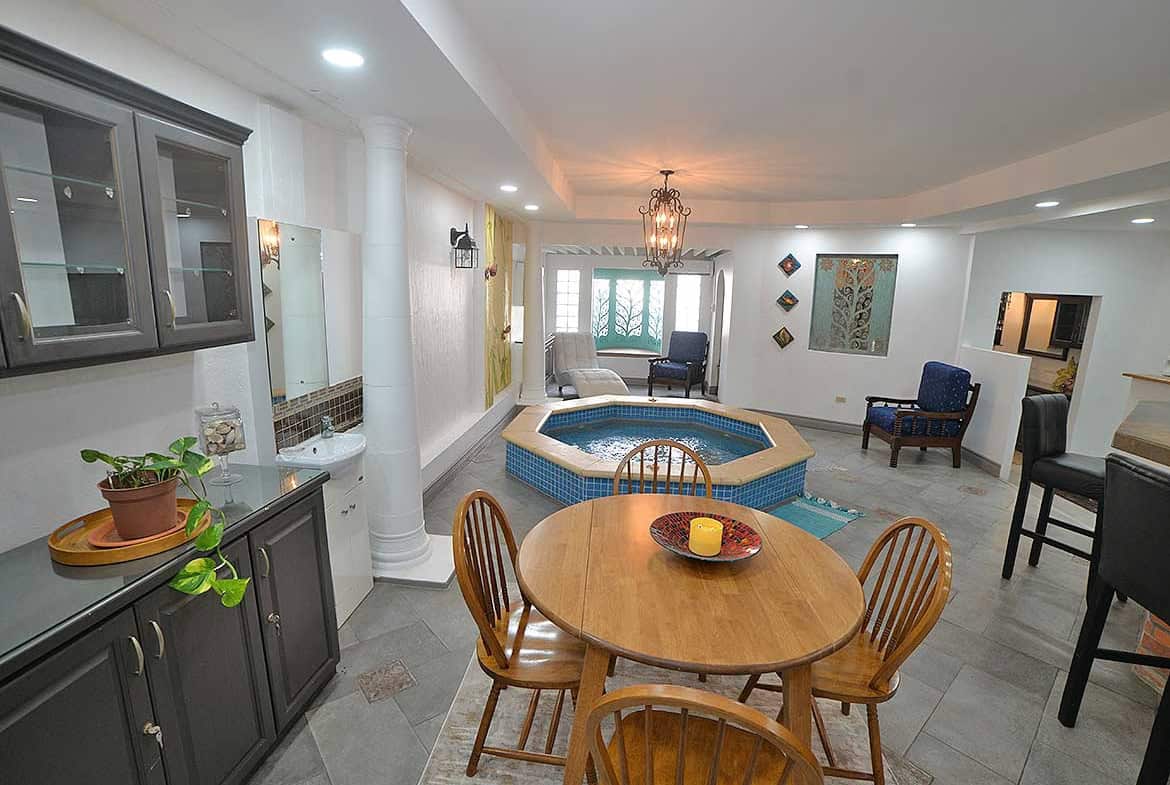 Cornerstone- Interior view of a living room with hot tub, dining area, and seating.
