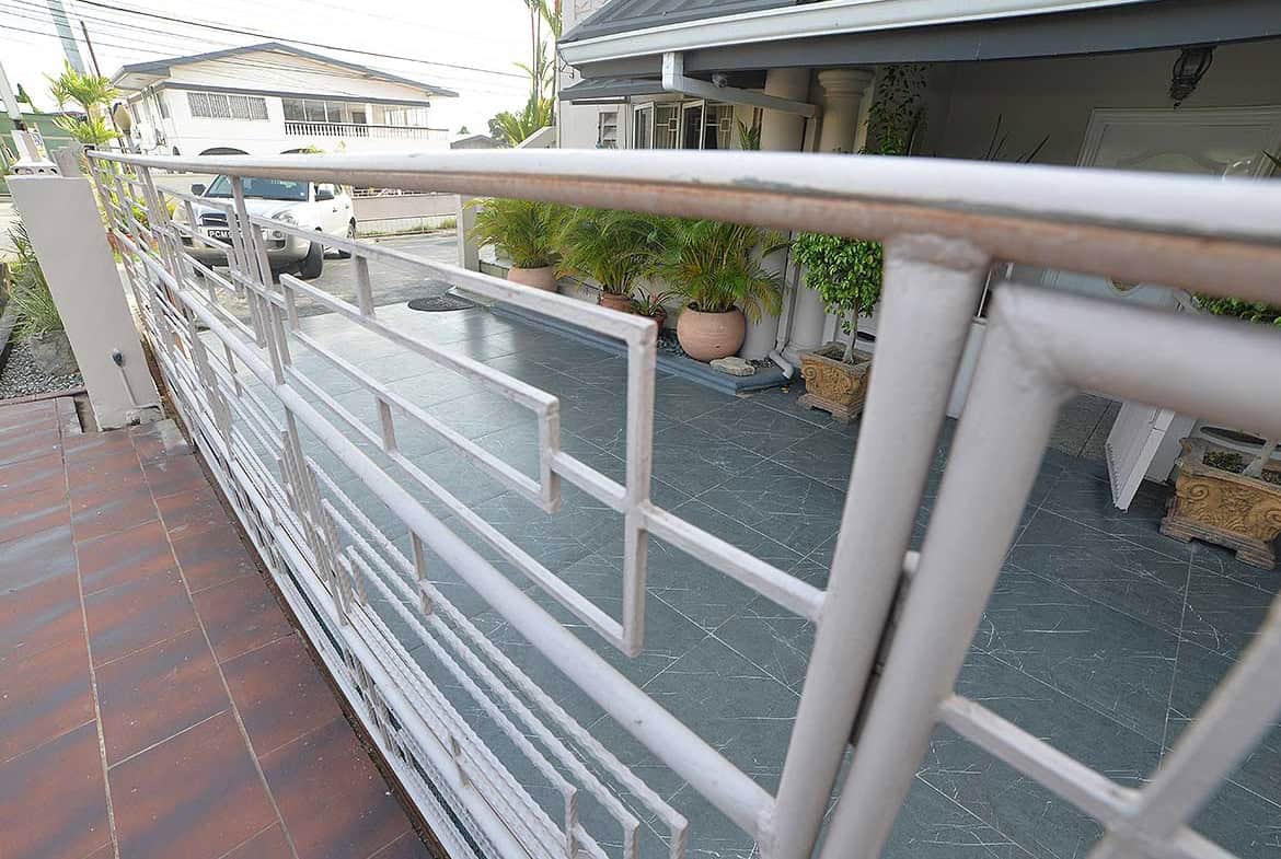 Cornerstone- Balcony with metal railing overlooking residential street and garden.