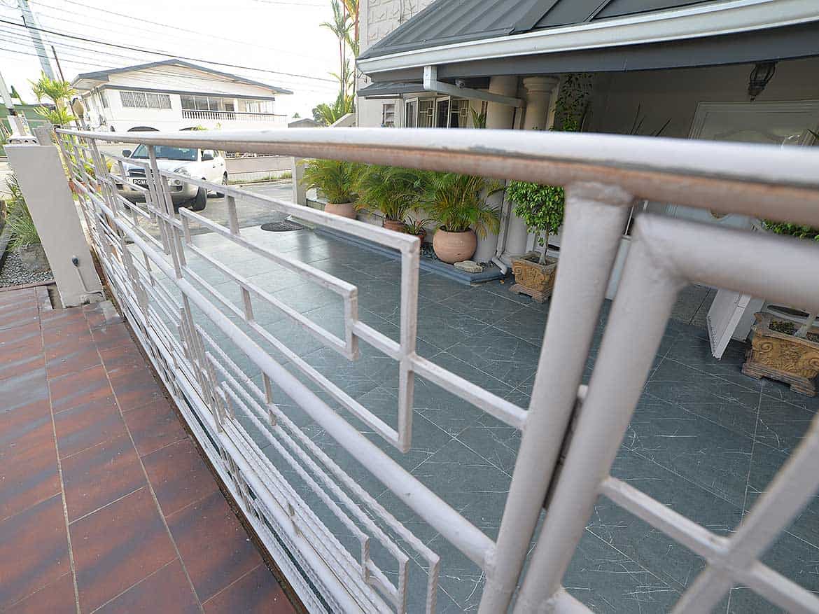 Balcony View of Cornerstone™ Property Cornerstone- Balcony with metal railing overlooking residential street and garden.