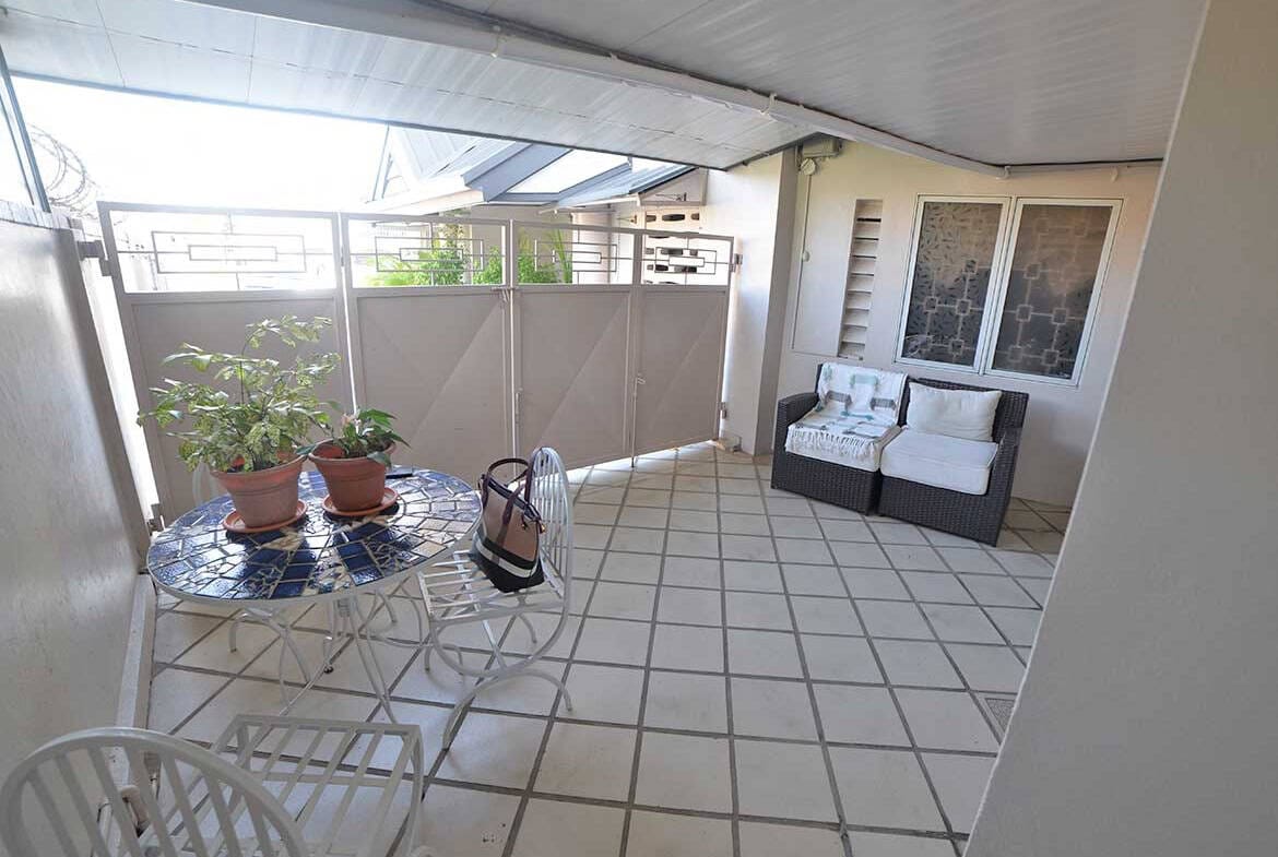 Cornerstone- Balcony with outdoor seating, potted plants, and a view of neighboring buildings.
