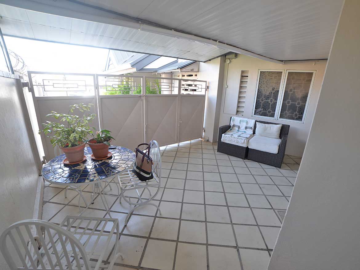 Spacious Balcony with Seating and Plants Cornerstone- Balcony with outdoor seating, potted plants, and a view of neighboring buildings.