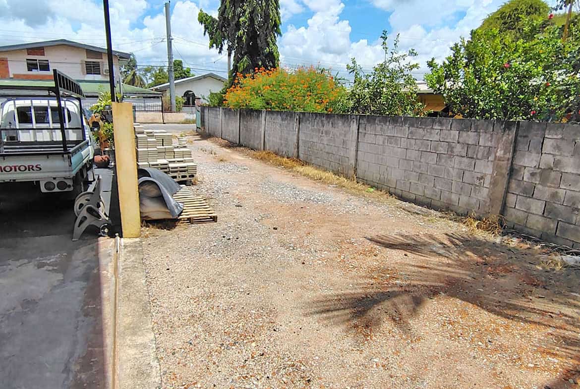 Cornerstone- Vacant lot with construction materials and a concrete wall, ready for development.