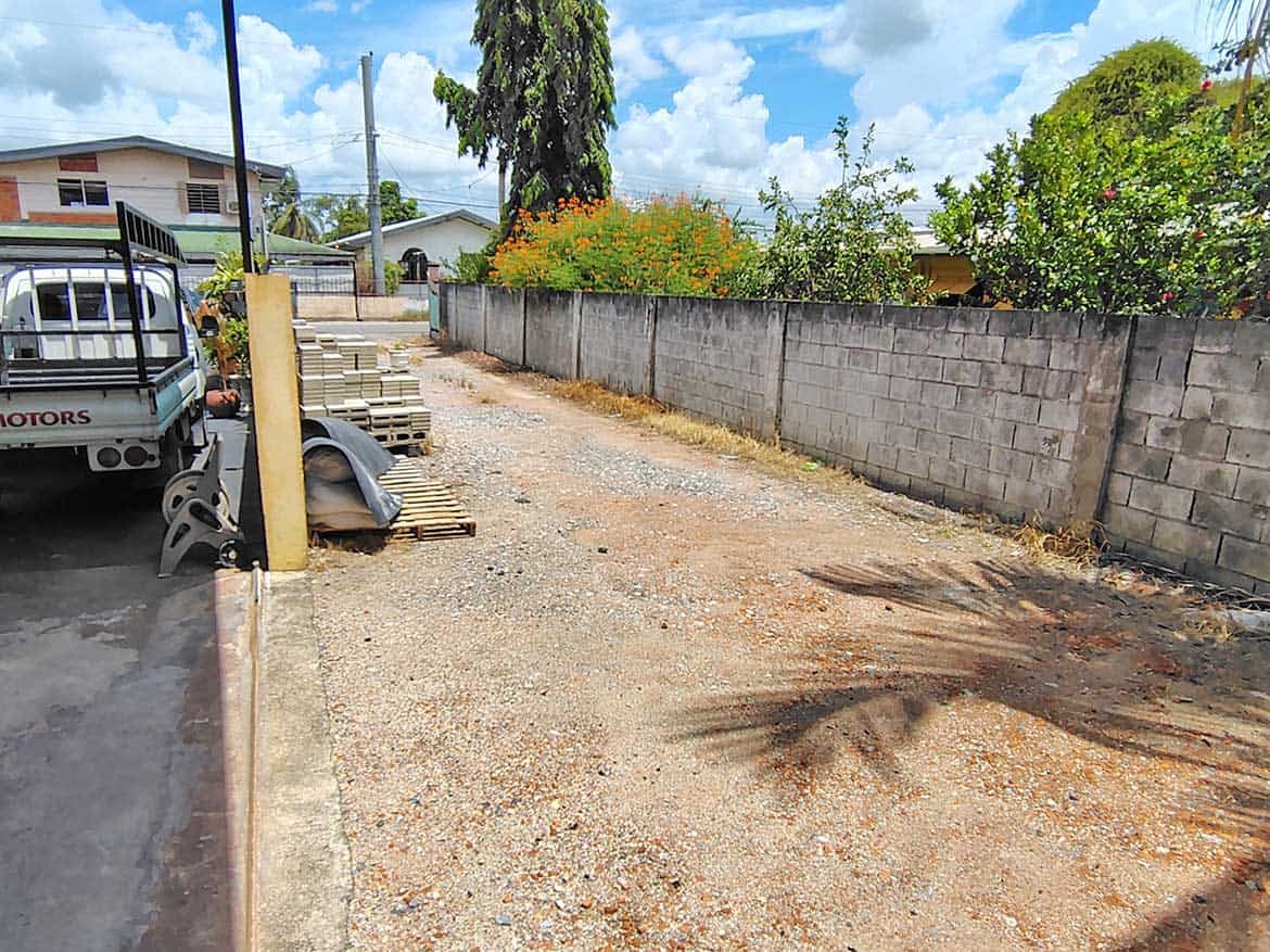 Construction Site for Residence with Retail Space Cornerstone- Vacant lot with construction materials and a concrete wall, ready for development.