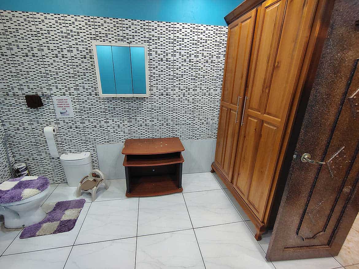 Modern Bathroom with Wooden Cabinet Cornerstone- Bathroom with toilet, wooden cabinet, and tiled wall design.