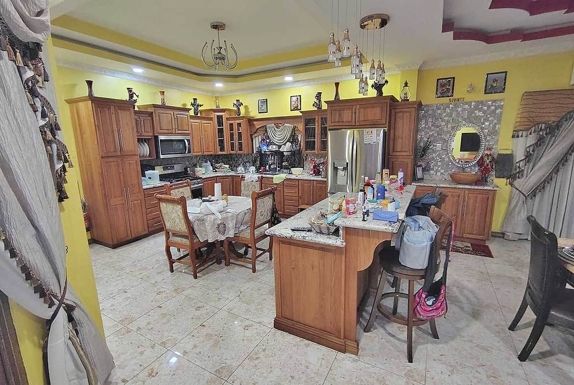 Cornerstone- Large kitchen with wooden cabinets, island, and dining area in a residence.