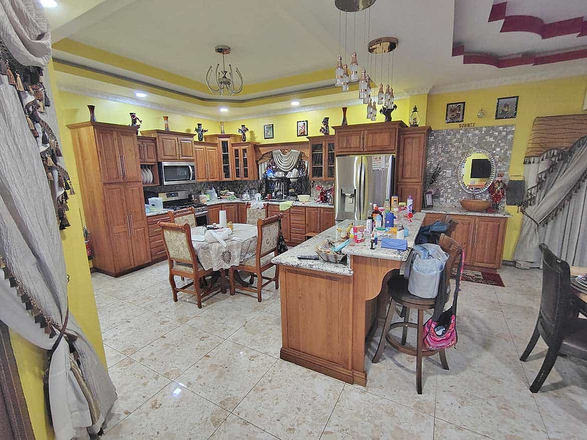 Spacious Kitchen with Modern Amenities Cornerstone- Large kitchen with wooden cabinets, island, and dining area in a residence.