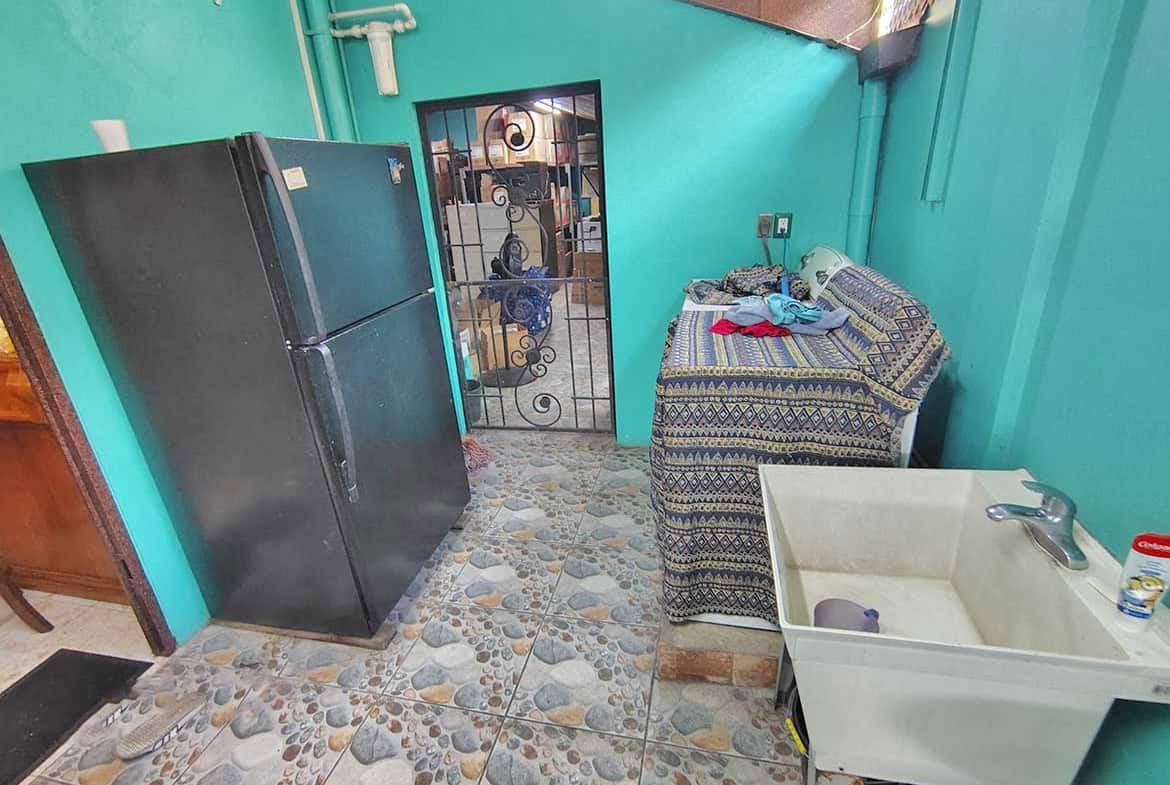 Cornerstone- Laundry room with refrigerator, sink, and laundry supplies in residence with retail space.