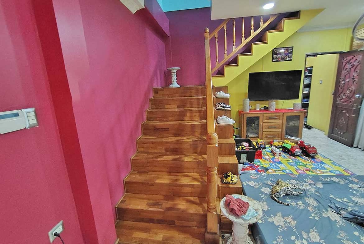 Cornerstone- Colorful living room with staircase and retail area in the background.