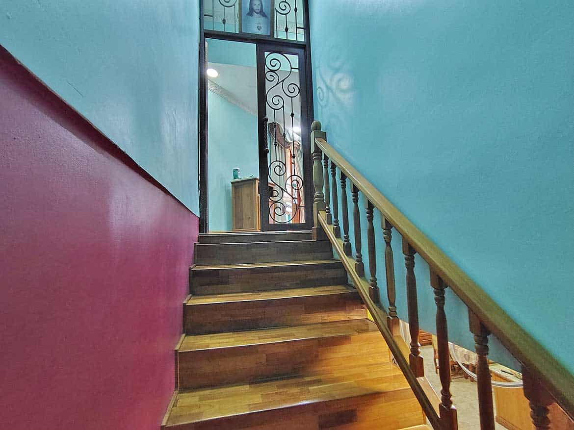 Interior Staircase at Residence with Retail Space Cornerstone- Colorful interior staircase with wooden steps and decorative iron gate at residence with retail.
