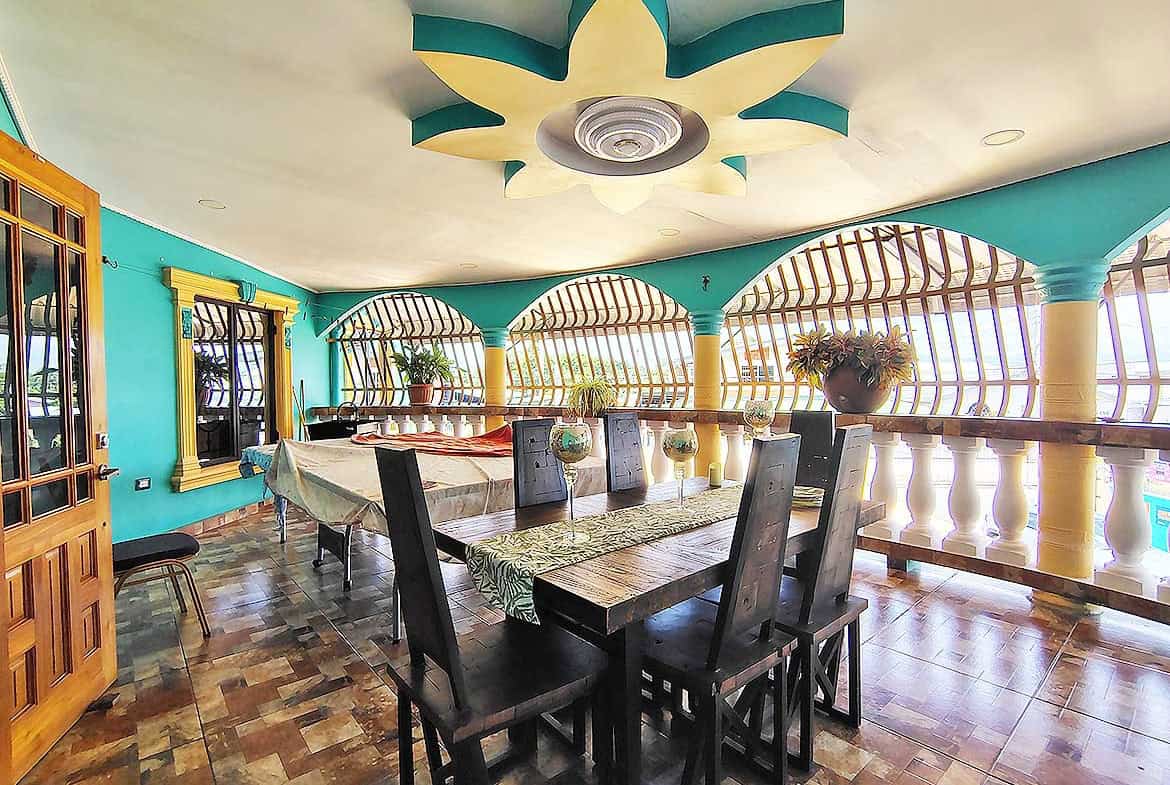 Cornerstone- Bright dining room with turquoise walls, wooden furniture, and decorative ceiling.