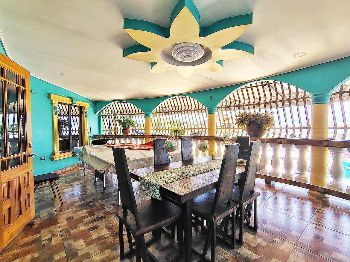 Colorful Dining Area with Unique Ceiling Design Cornerstone- Bright dining room with turquoise walls, wooden furniture, and decorative ceiling.