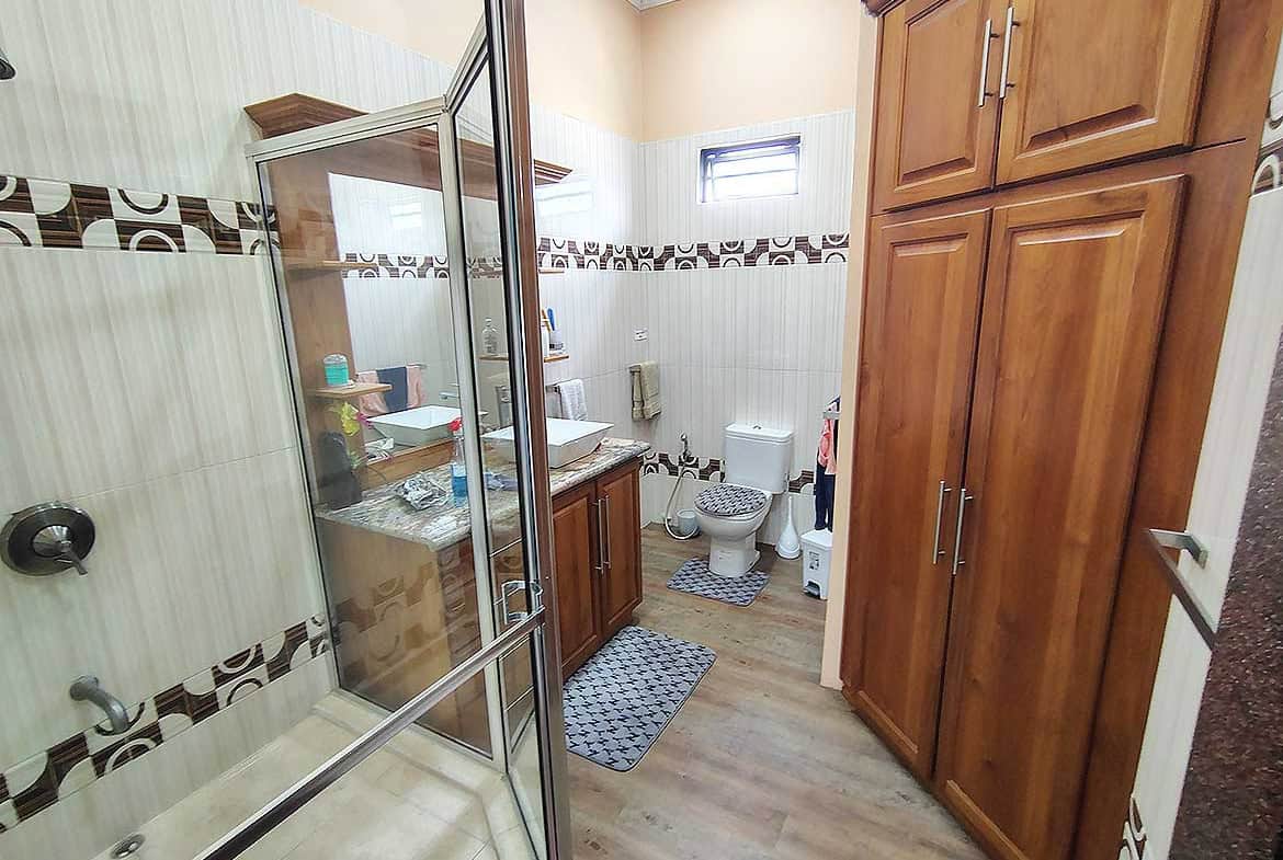 Cornerstone- Bathroom with wooden cabinets, shower, and toilet in residence with retail space.