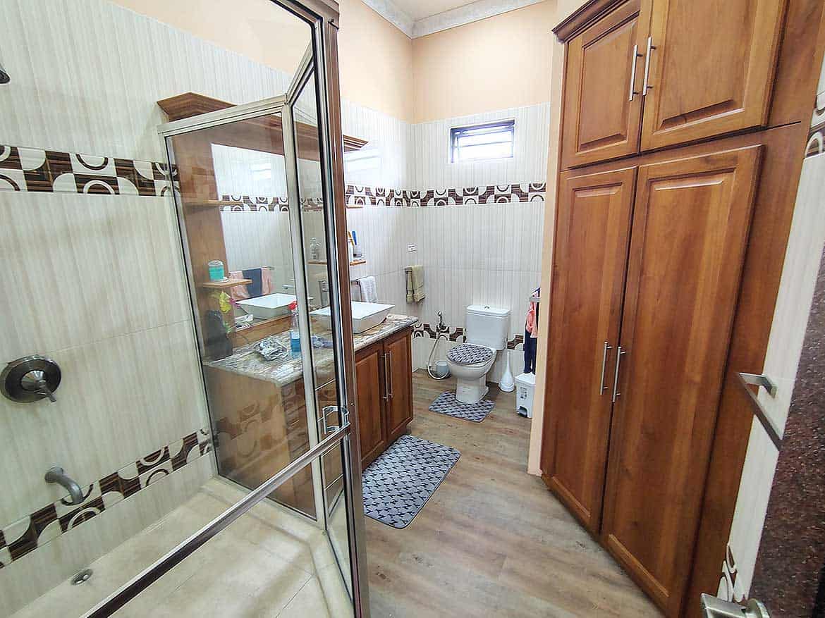 Bathroom with Wooden Cabinets and Shower Cornerstone- Bathroom with wooden cabinets, shower, and toilet in residence with retail space.