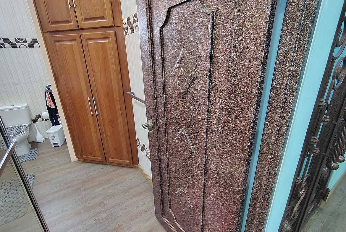 Cornerstone- Residential door with decorative design in a home with wooden cabinets.