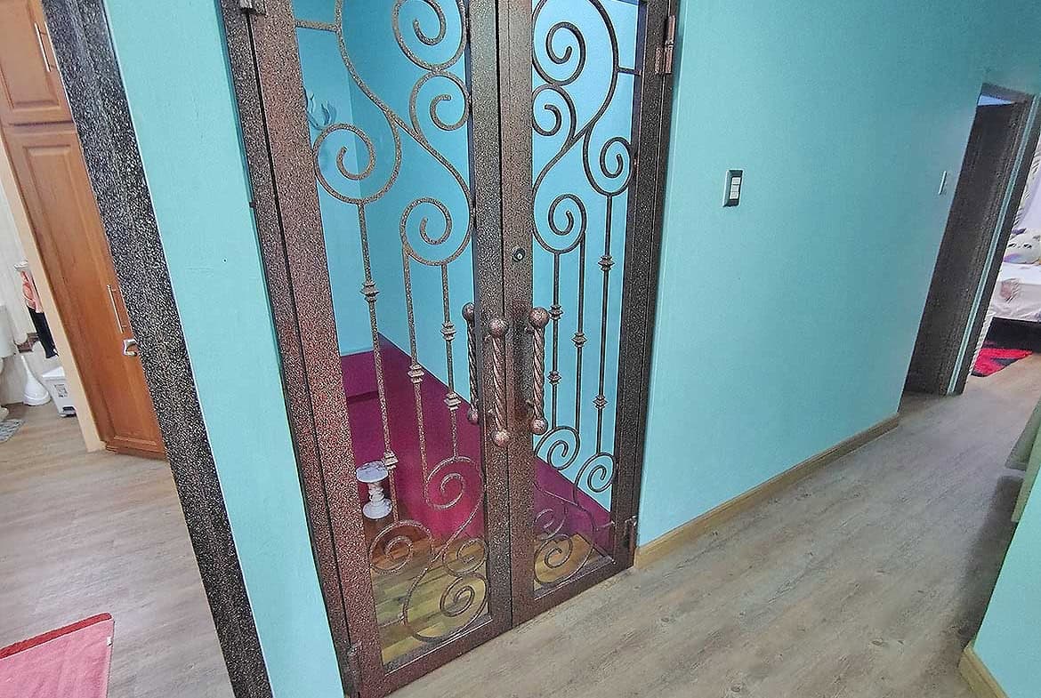 Cornerstone- Decorative iron door with glass panels in a modern residence.