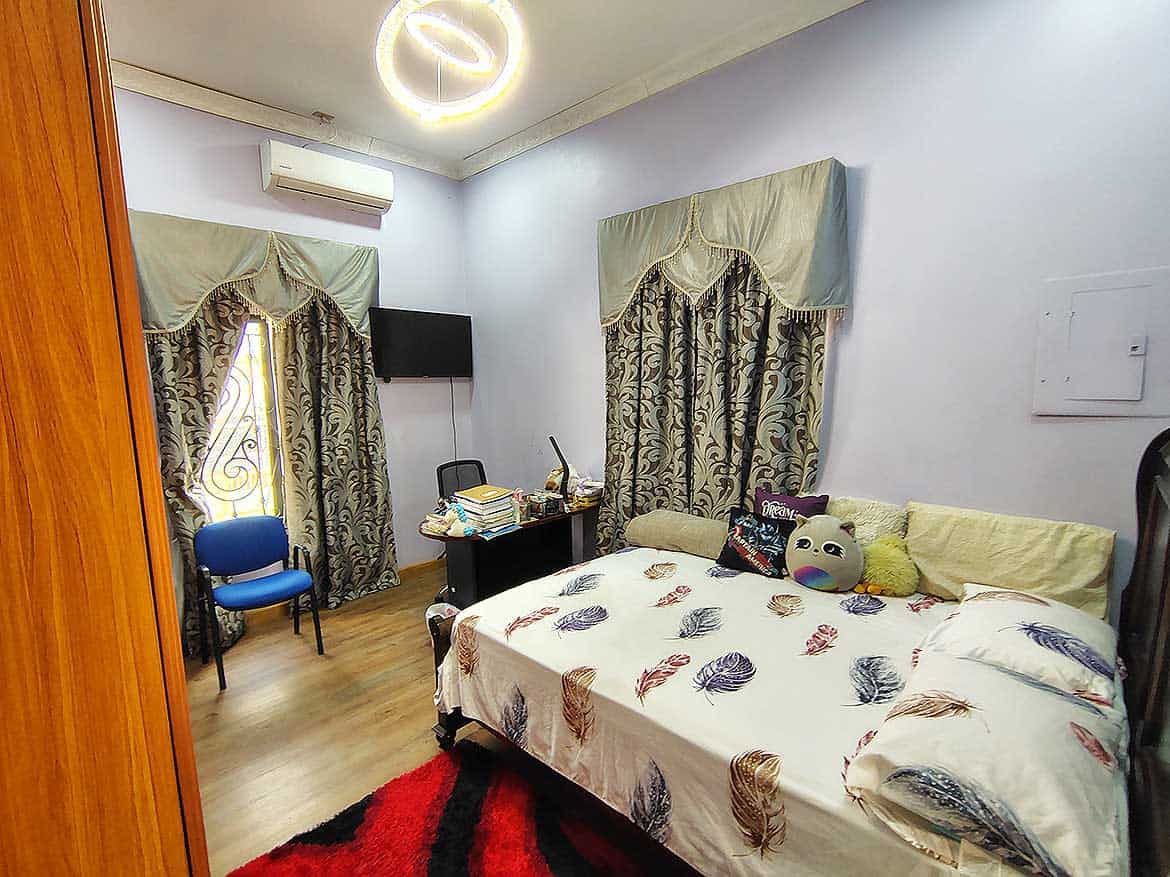 Interior of a Residential Room with Retail Space Cornerstone- Cozy bedroom with bed, curtains, and workspace in a residential retail property.