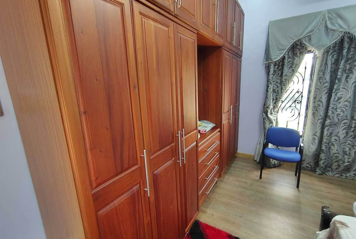 Cornerstone- Interior view of a residence with wooden cabinets and a window with curtains.