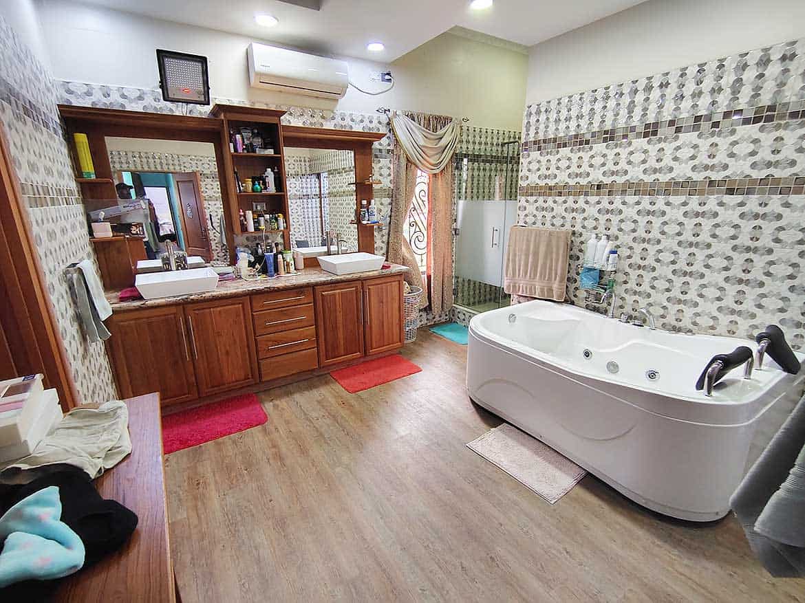 Luxury Bathroom with Jacuzzi and Vanity Cornerstone- Spacious bathroom with Jacuzzi tub, wooden vanity, and decorative wall tiles.