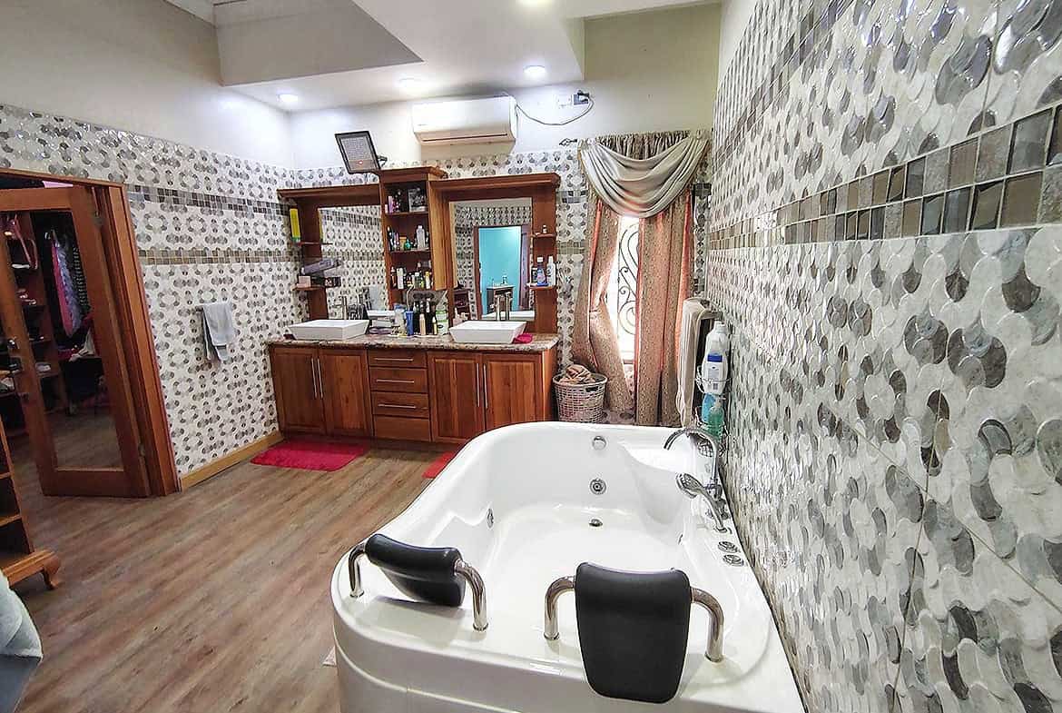 Cornerstone- Spa bathroom with bathtub, wooden cabinets, and decorative wall tiles.