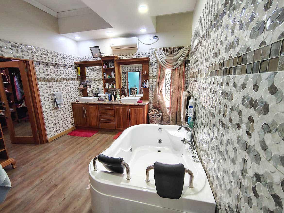 Residence with Spa Bathroom Cornerstone- Spa bathroom with bathtub, wooden cabinets, and decorative wall tiles.