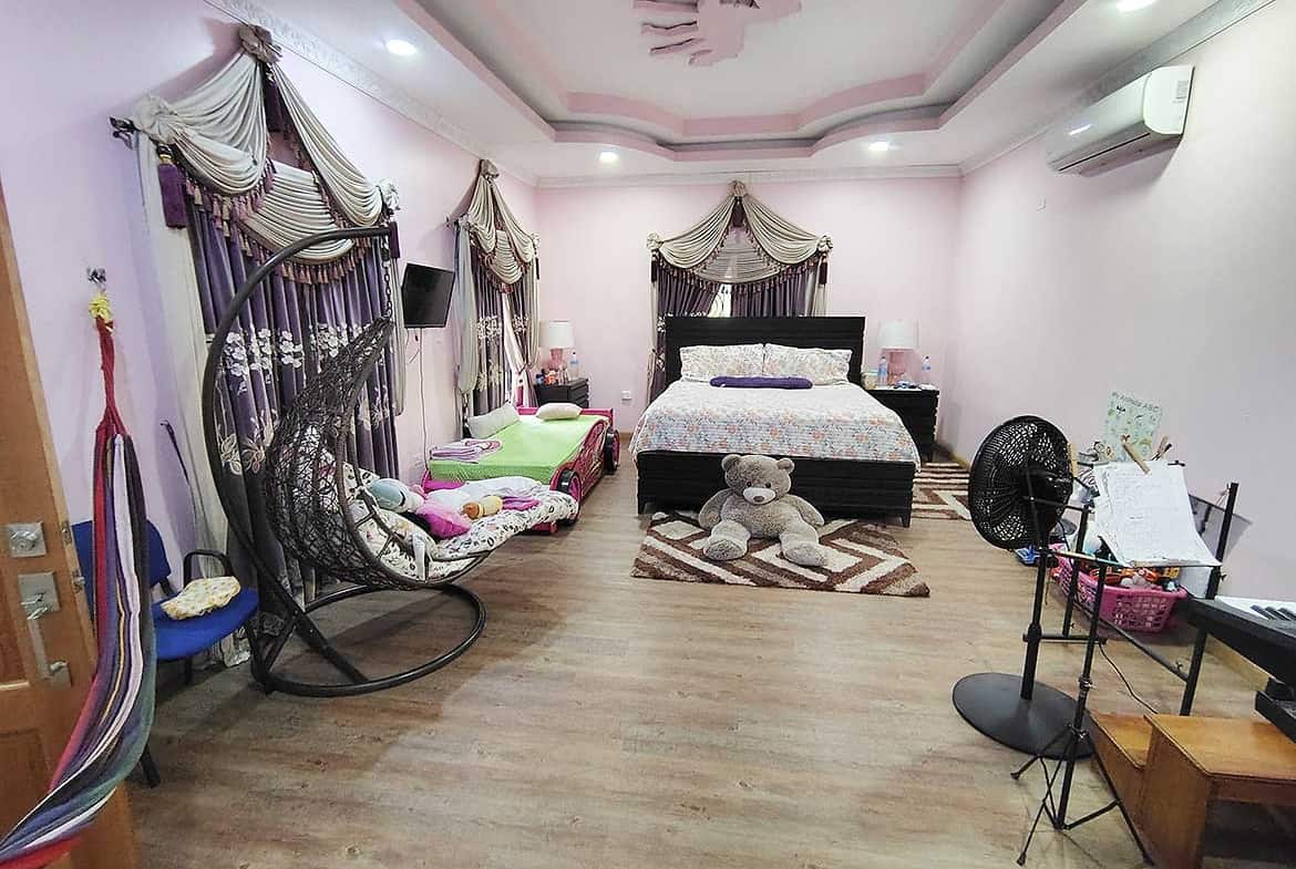 Cornerstone- Large bedroom with pink walls, canopy bed, and cozy seating area.