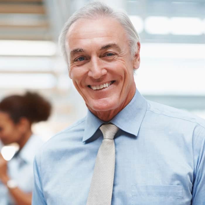 Cornerstone- Smiling senior man in business attire at Cornerstone™ office.