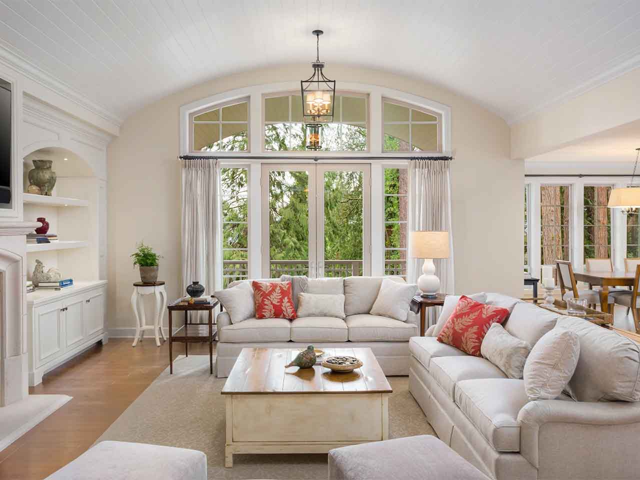 Cornerstone- Bright living room with large arched windows and white sofas.