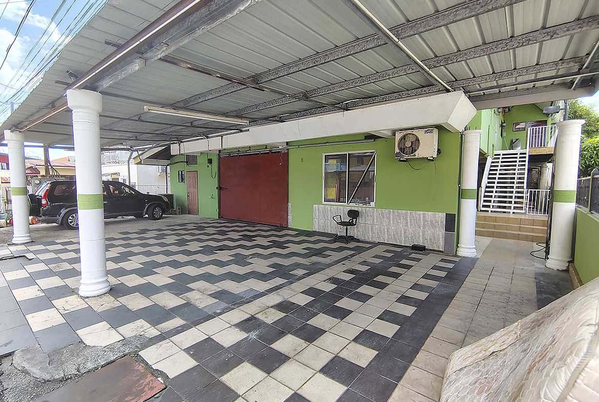 Cornerstone- Covered parking area at Ganga Terrace in El Socorro with green walls and checkered floor.