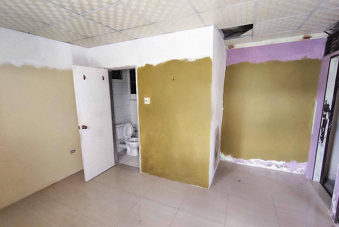 Cornerstone- Room under renovation with partially painted walls and bathroom visible.
