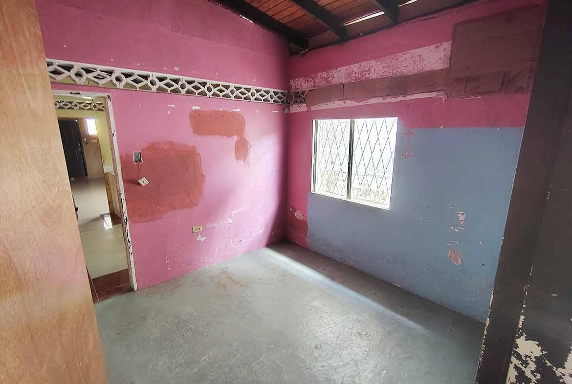 Cornerstone- Empty room with pink and blue walls, window, and wooden ceiling.