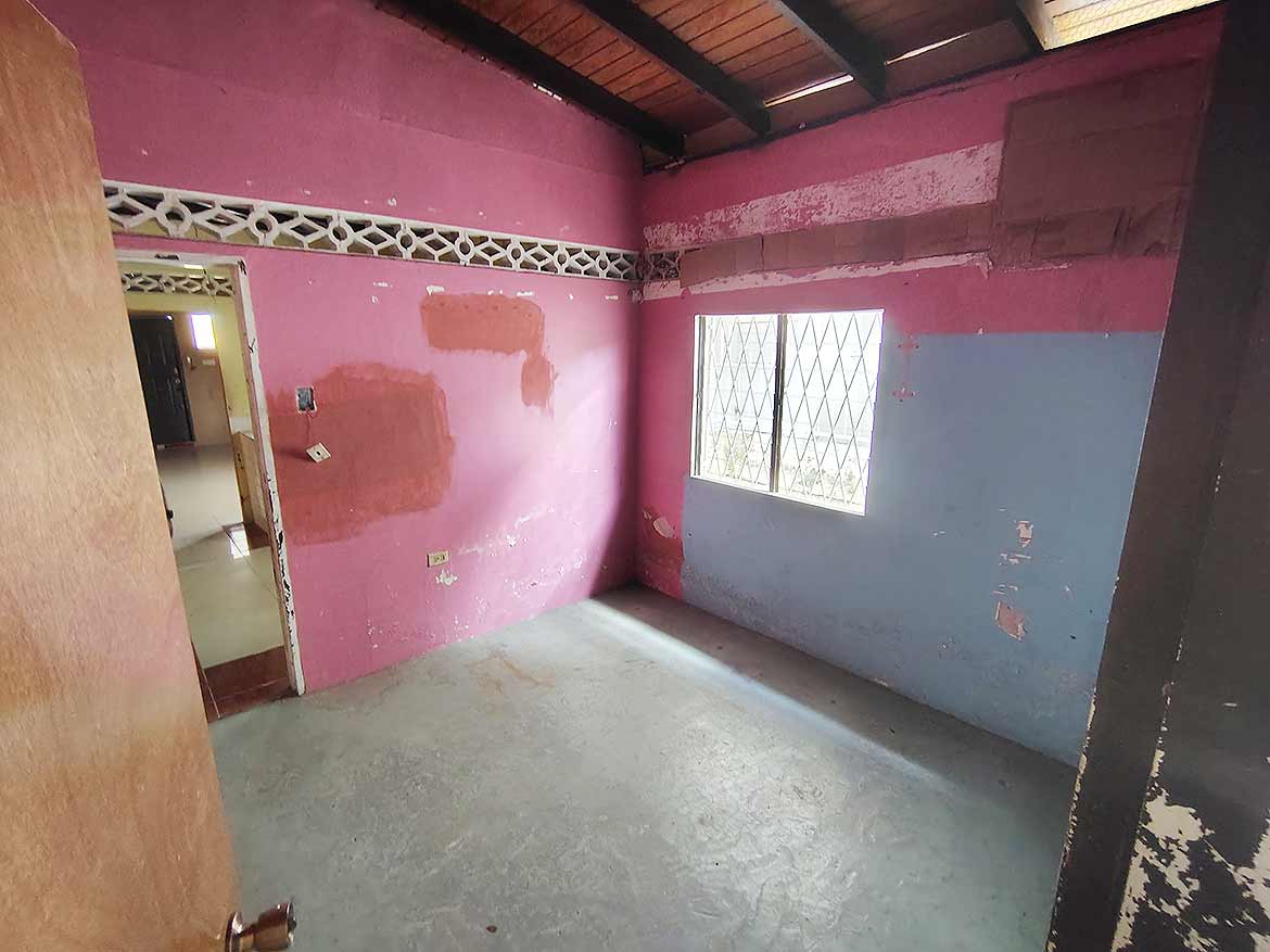 Interior of Ganga Terrace Room Cornerstone- Empty room with pink and blue walls, window, and wooden ceiling.