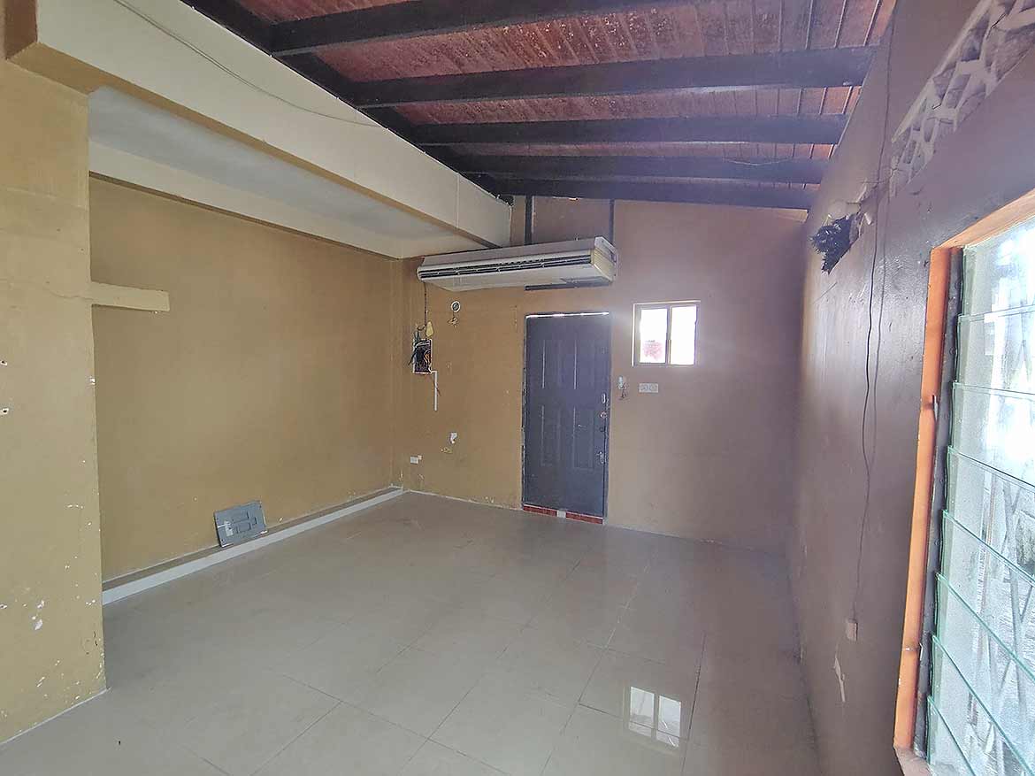 Interior of Ganga Terrace, El Socorro Cornerstone- Spacious room with high wooden ceiling and air conditioning unit.