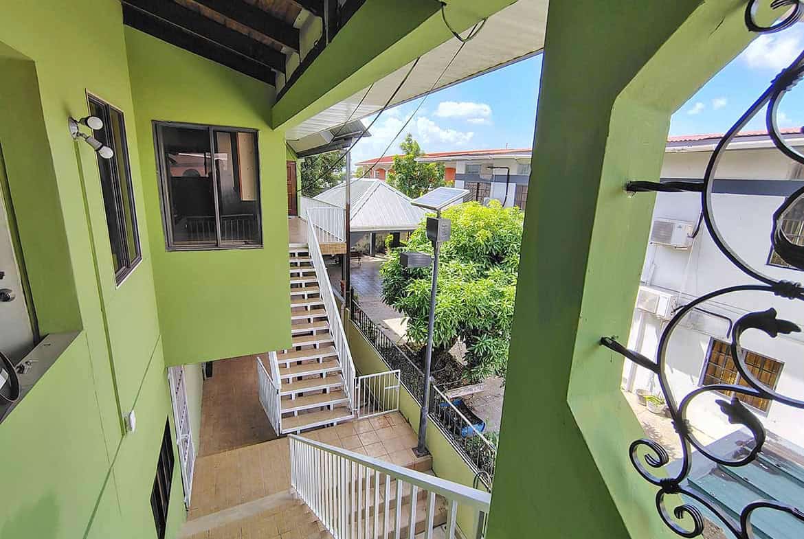 Cornerstone- Balcony view from Ganga Terrace in El Socorro with greenery and neighboring buildings.