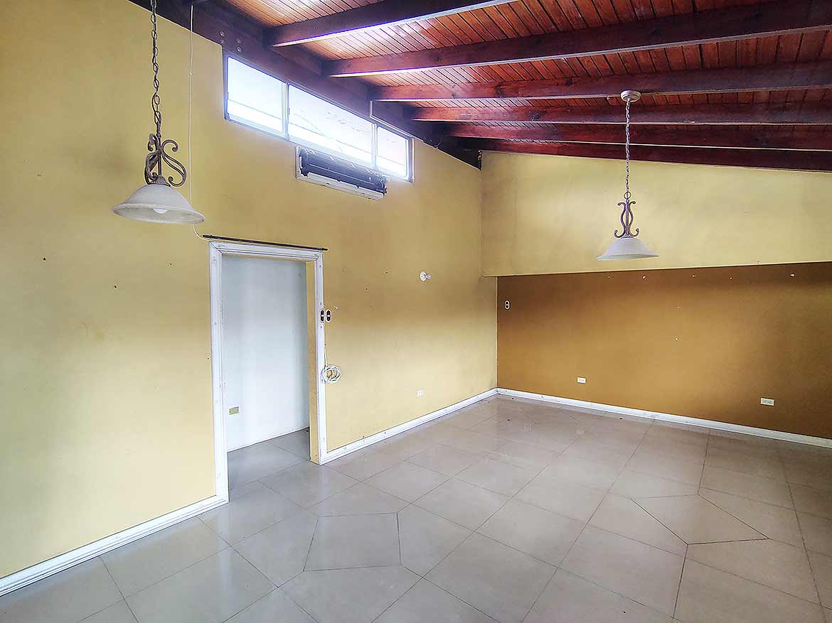 Spacious Room at Ganga Terrace Cornerstone- Bright, empty room with wooden ceiling and large windows in Ganga Terrace.