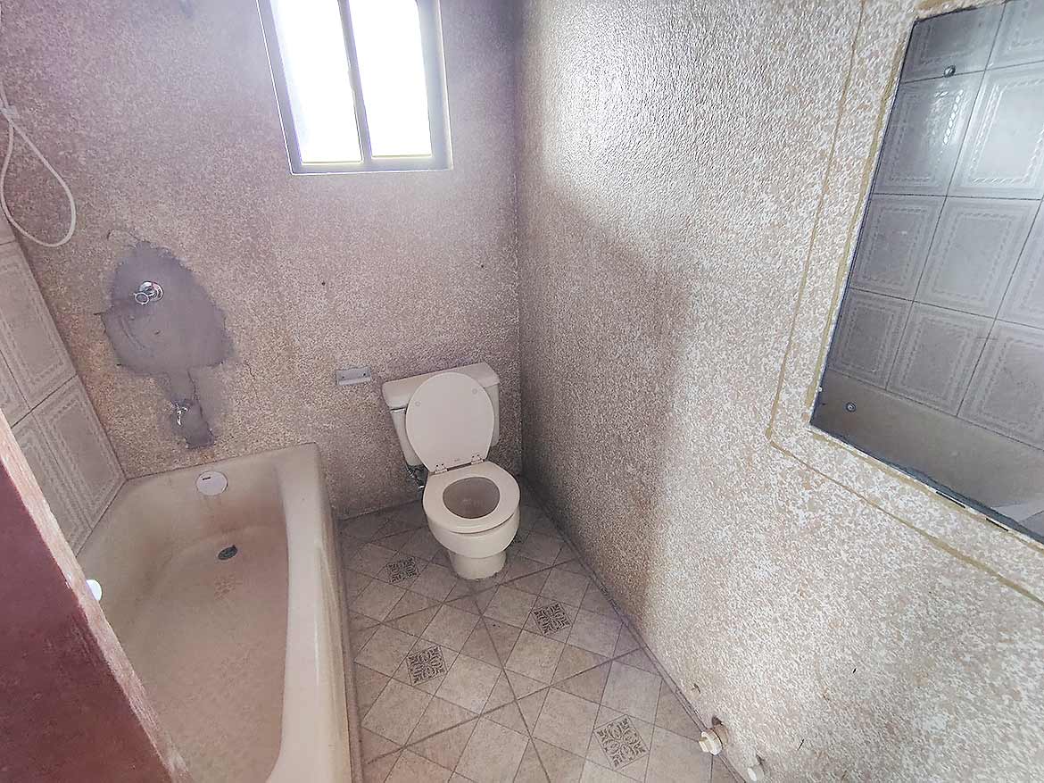Small bathroom with basic fixtures Cornerstone- Small bathroom with bathtub, toilet, and mirror in a modest setting.