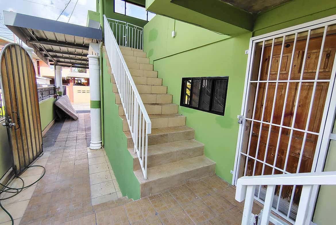 Cornerstone- Green building exterior with staircase and sliding door at Ganga Terrace.