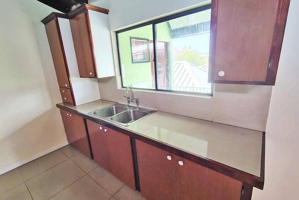 Cornerstone- Modern kitchen with wooden cabinets and stainless steel sink in Ganga Terrace.