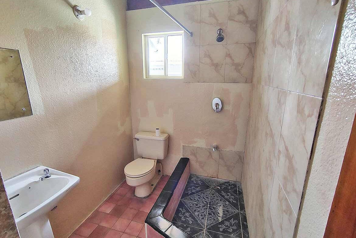 Cornerstone- Bathroom with toilet, sink, and shower area at Ganga Terrace.
