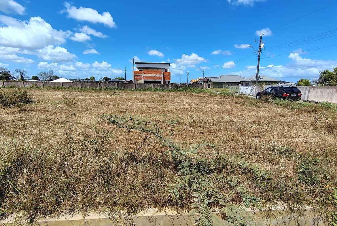 Cornerstone- Empty plot of land on St Louis Dr, Longdenville with clear sky and nearby buildings.