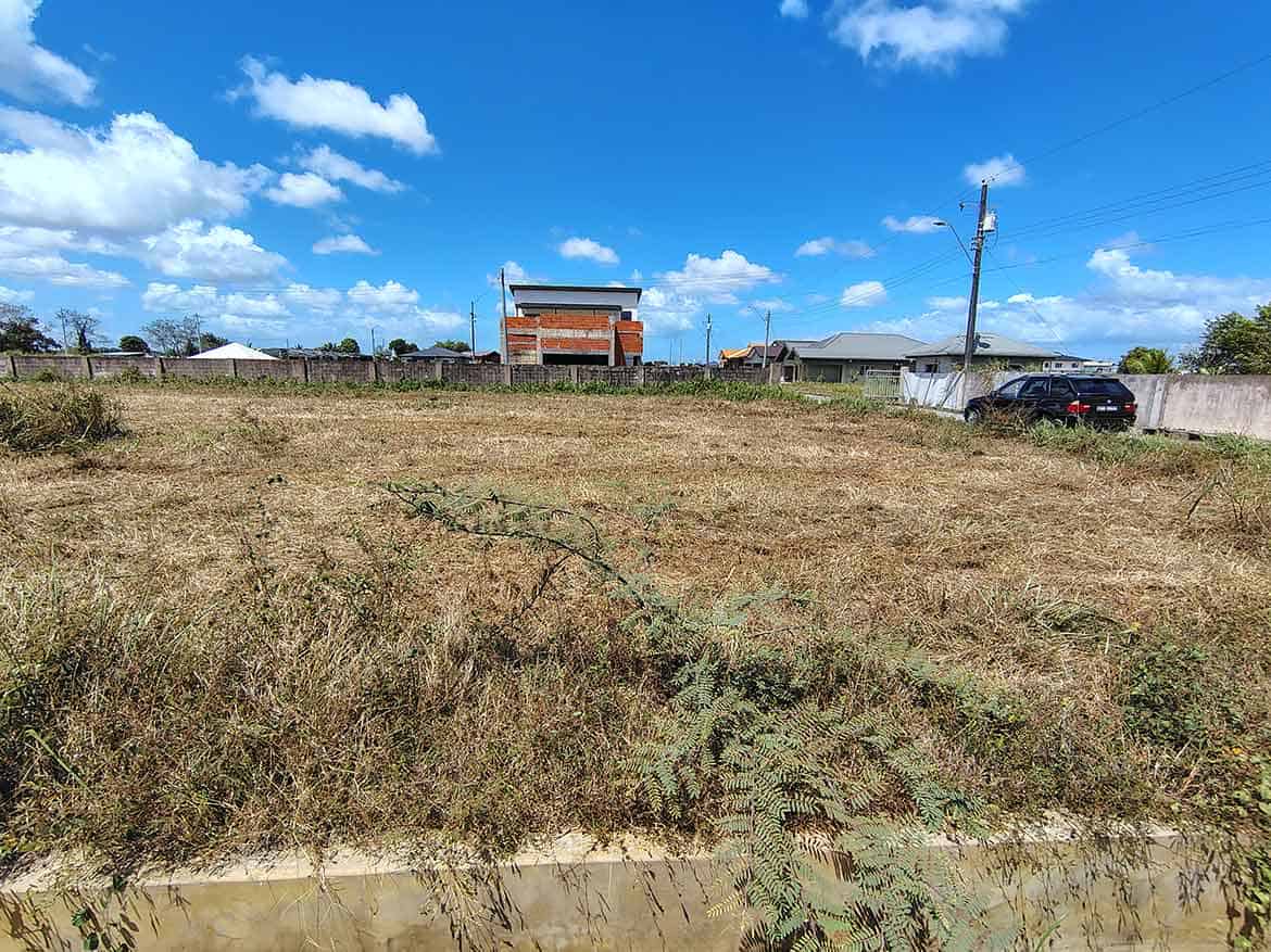 Cornerstone- Empty plot of land on St Louis Dr, Longdenville with clear sky and nearby buildings.