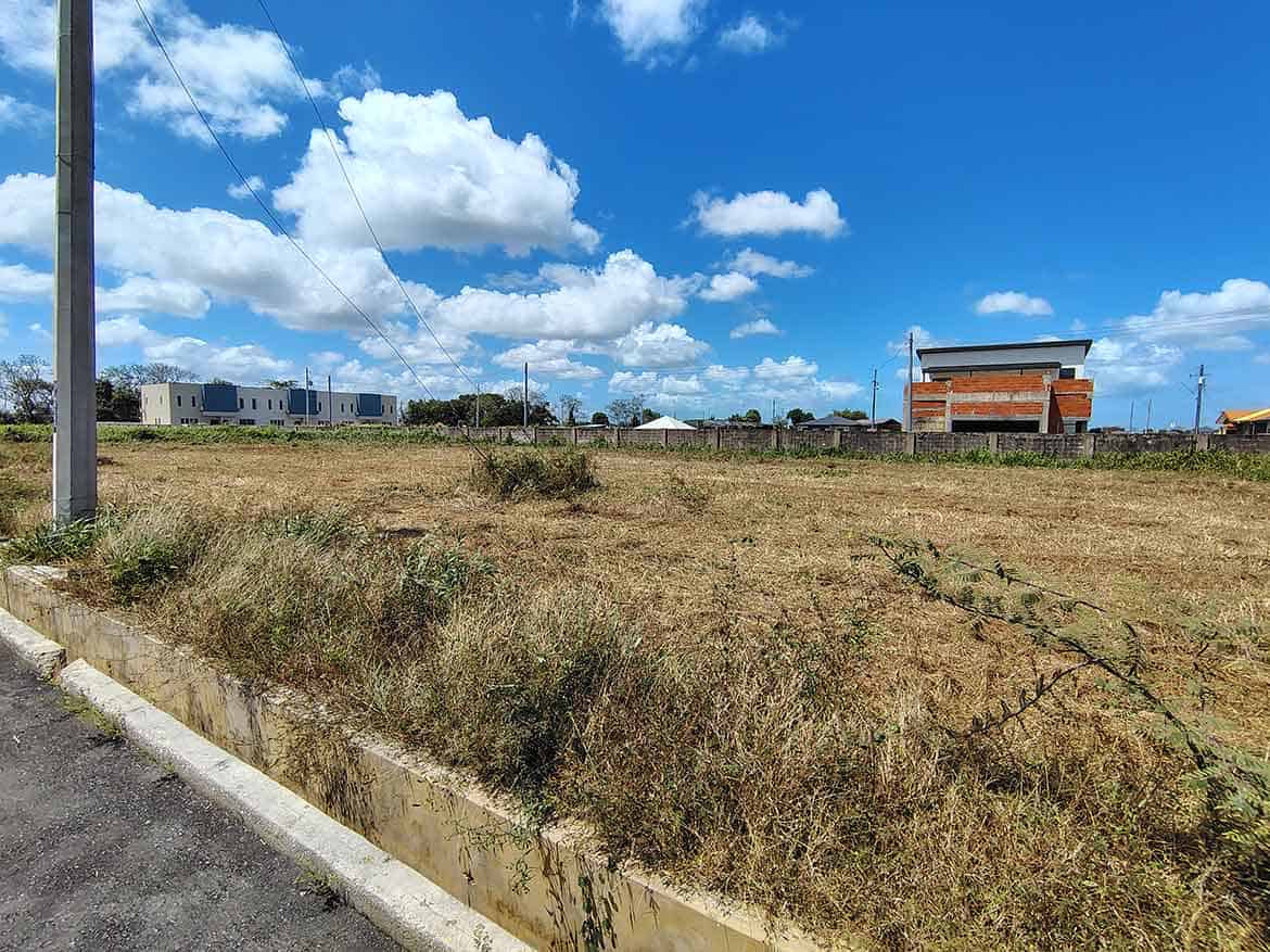 Cornerstone- Open grassy land with buildings in the background near St Louis Dr, Longdenville.
