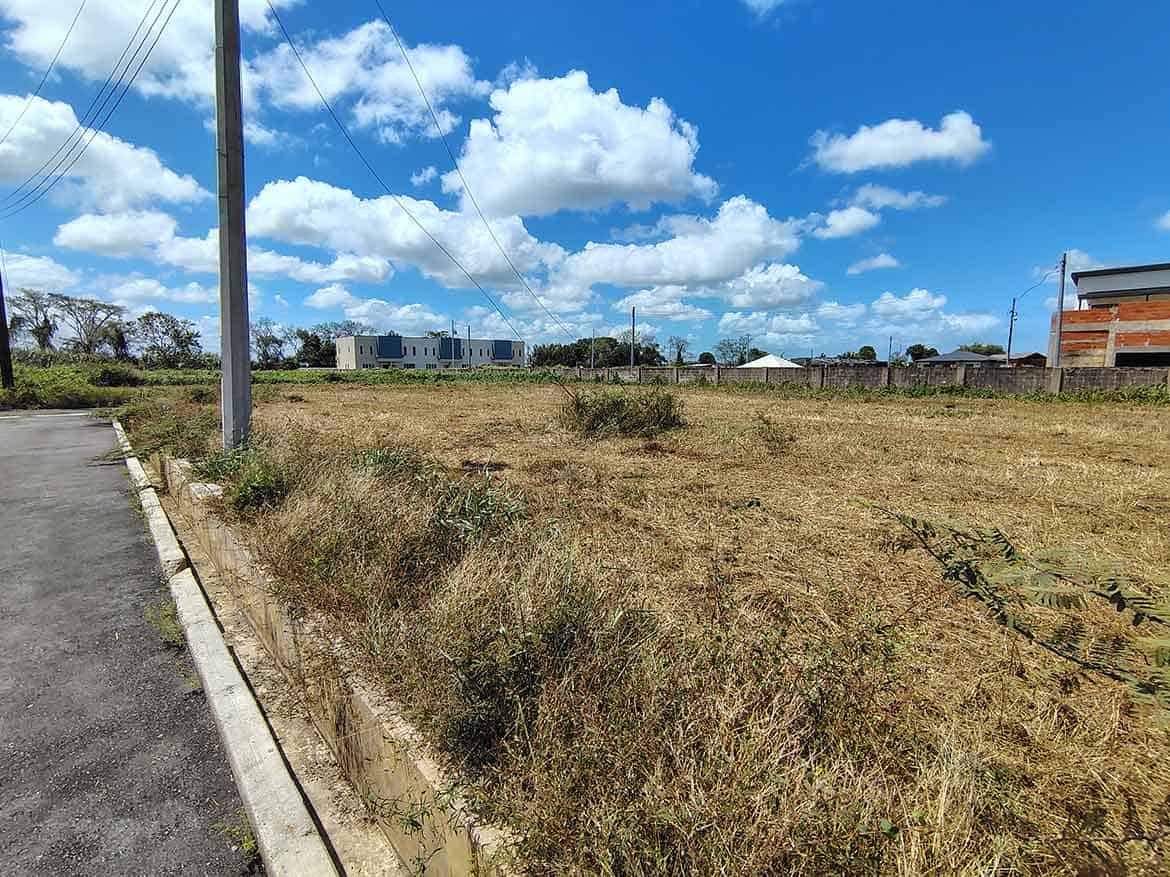 Cornerstone- Vacant land plot in Longdenville with clear sky and nearby buildings.