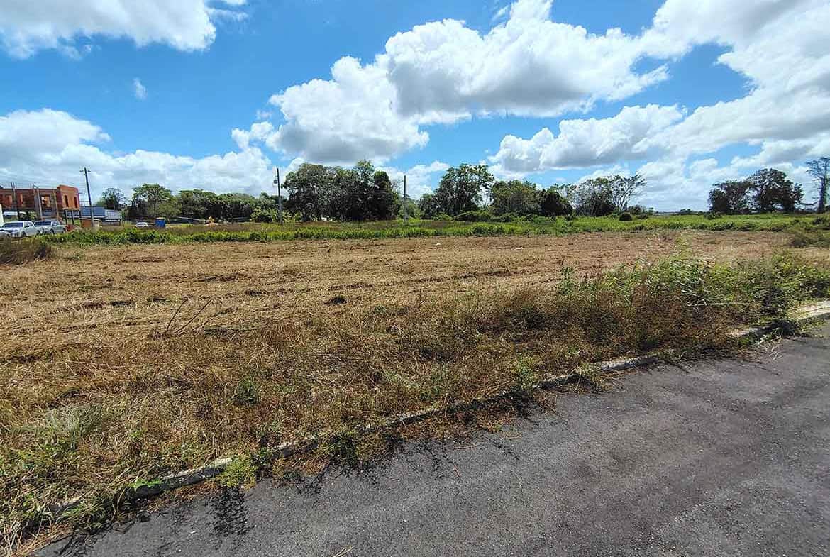 Cornerstone- Empty plot of land on St Louis Dr, Longdenville under a blue sky with clouds.
