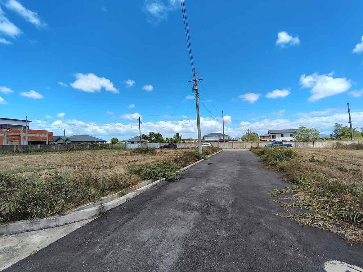 Cornerstone- Newly paved street in Longdenville with utility poles and houses in the background.