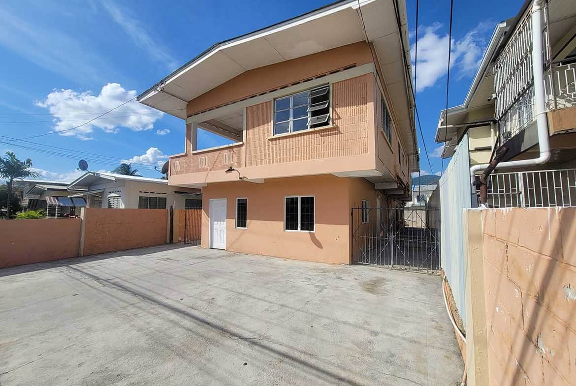 Cornerstone- Modern two-story residential building in Tacarigua with spacious driveway and clear blue sky.
