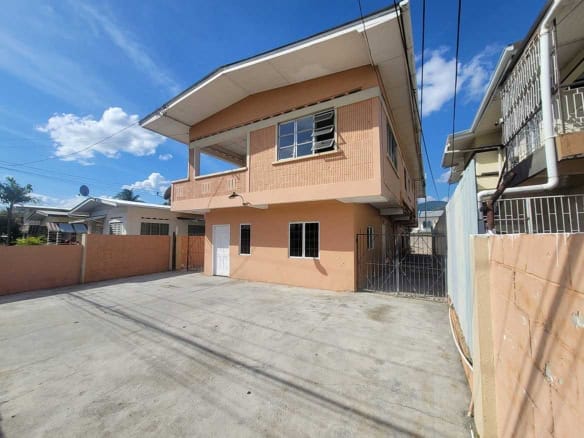 Cornerstone- Modern two-story residential building in Tacarigua with spacious driveway and clear blue sky.