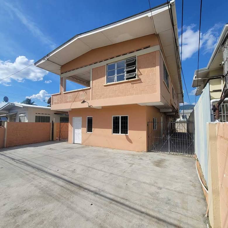 Cornerstone- Modern two-story residential building in Tacarigua with spacious driveway and clear blue sky.