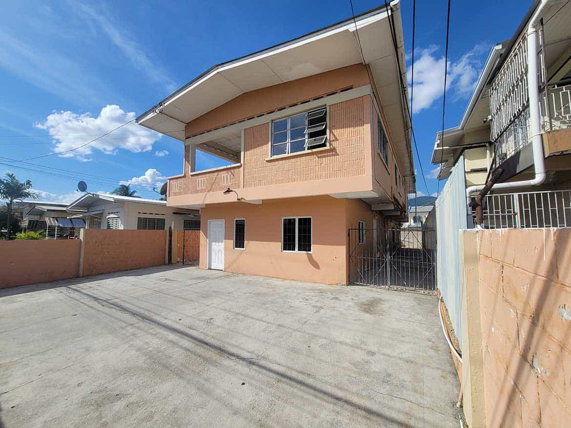 Cornerstone- Modern two-story residential building in Tacarigua with spacious driveway and clear blue sky.
